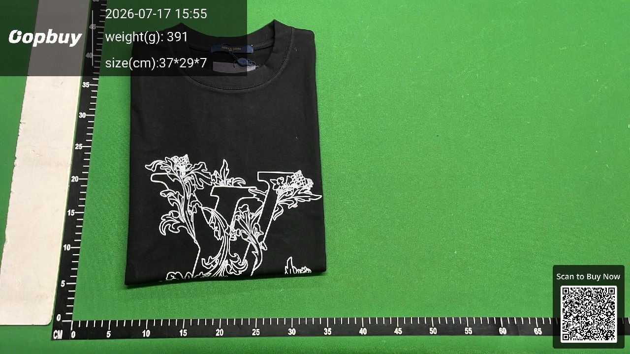 Folded dark T-shirt with a printed front on an Oopbuy measuring mat